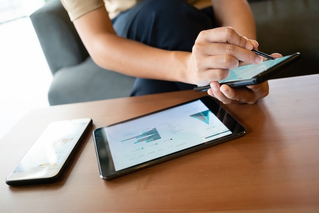 Mujer asiática que mira algunas cartas en su teléfono móvil mientras está sentada en la cafetería