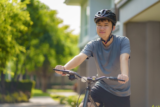 Mujer asiática que parece feliz mientras anda en bicicleta por su vecindario para la salud y el bienestar diario, tanto físico como mental.