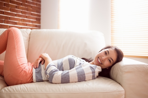 Mujer asiática que se relaja en el sofá