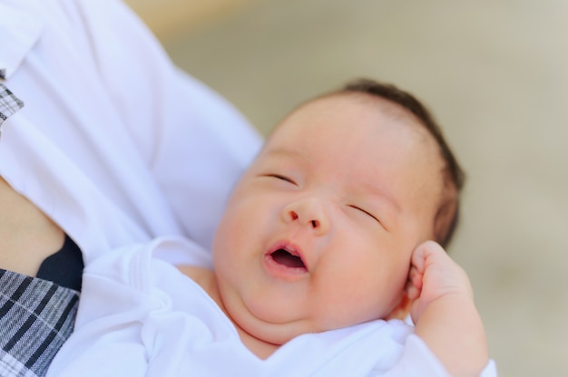 Mujer asiática que sostiene a un bebé recién nacido en sus brazos en casa. Día de la madre y concepto recién nacido del cuidado de la salud del bebé recién nacido.