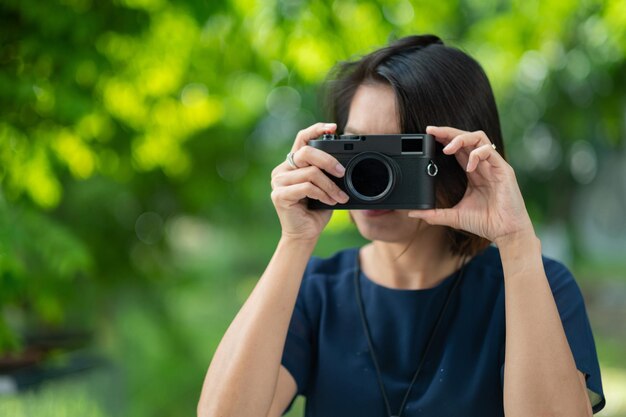 Mujer asiática que sostiene un fotógrafo profesional de la cámara