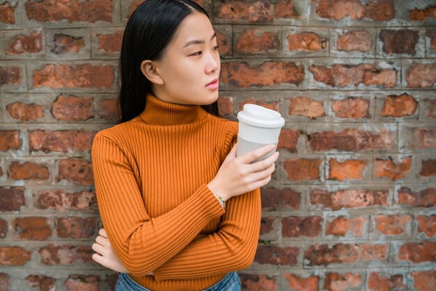 Mujer asiática que sostiene una taza de café