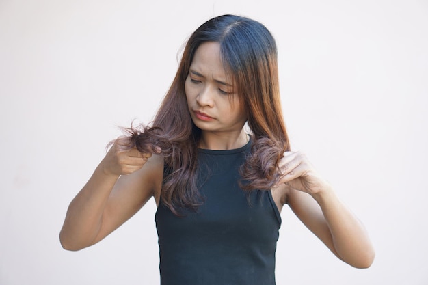 Mujer asiática que tiene picazón en la cabeza por la caspa