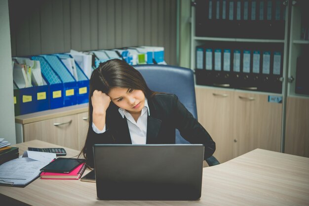 Mujer asiática que trabaja en la oficina Mujer de negocios joven estresada por la sobrecarga de trabajo con un montón de archivos en el escritorio Gente tailandesa pensando en algo