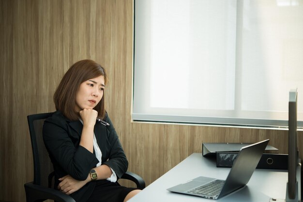 Mujer asiática que trabaja en la oficina Mujer de negocios joven estresada por la sobrecarga de trabajo con un montón de archivos en el escritorio Gente de Tailandia Concepto de pensamiento de trabajador