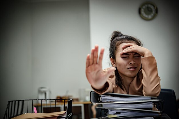 Mujer asiática que trabaja en la oficina Mujer de negocios joven estresada por la sobrecarga de trabajo con mucho archivo en el escritorio