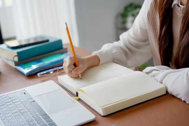 Mujer asiática que usa una computadora portátil para estudiar estudiante involucrado en aprendizaje en línea en la universidad