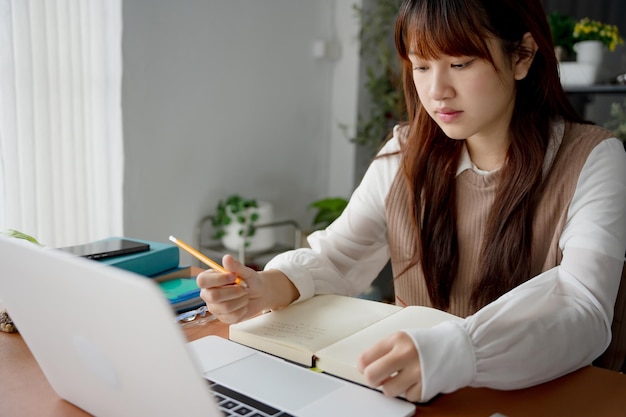 Mujer asiática que usa una computadora portátil para estudiar estudiante involucrado en aprendizaje en línea en la universidad