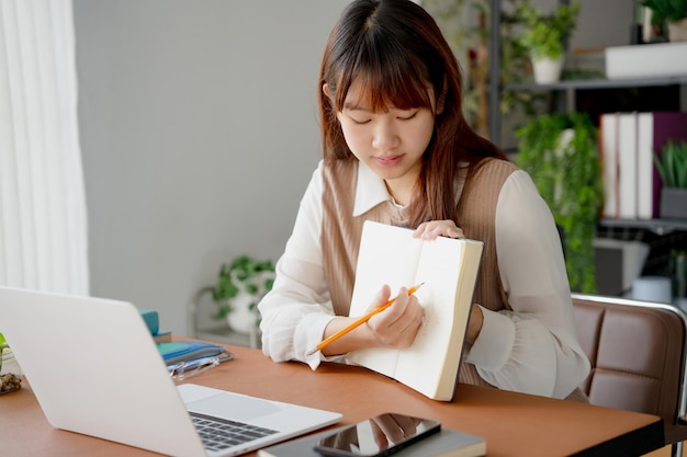 Mujer asiática que usa una computadora portátil para estudiar estudiante involucrado en aprendizaje en línea en la universidad