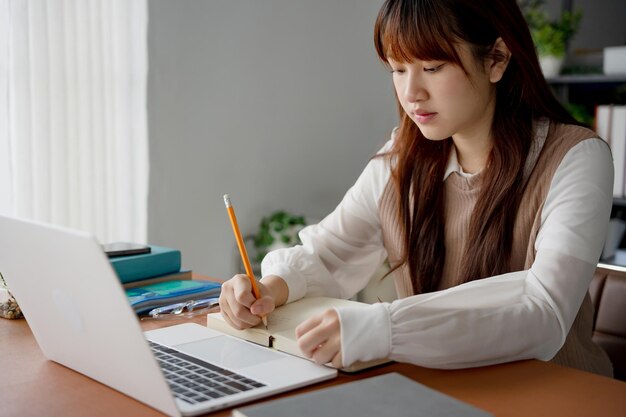Mujer asiática que usa una computadora portátil para estudiar estudiante involucrado en aprendizaje en línea en la universidad