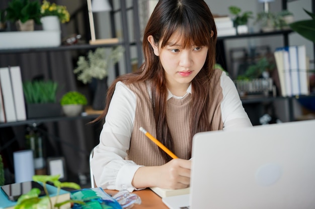 Mujer asiática que usa una computadora portátil para estudiar estudiante involucrado en aprendizaje en línea en la universidad