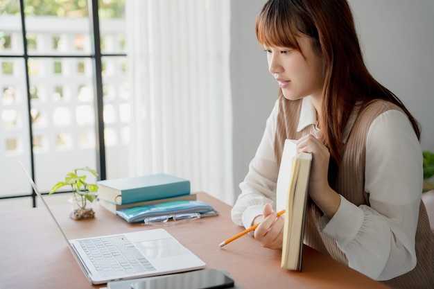 Mujer asiática que usa una computadora portátil para estudiar estudiante involucrado en aprendizaje en línea en la universidad