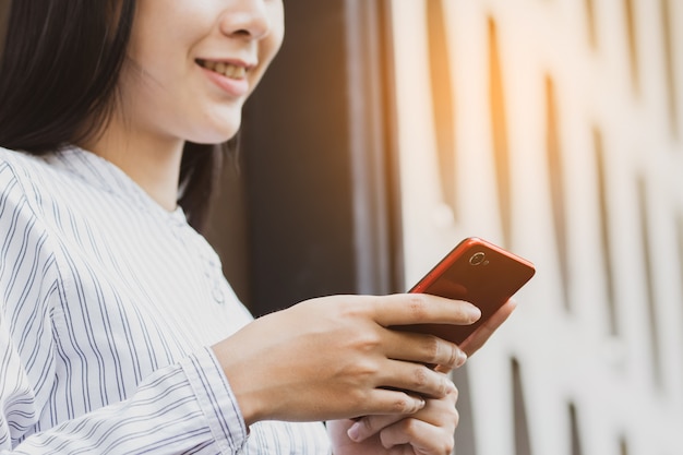 La mujer asiática que usa el funcionamiento del smartphone, jugando en tiempo libre con relaja y feliz.