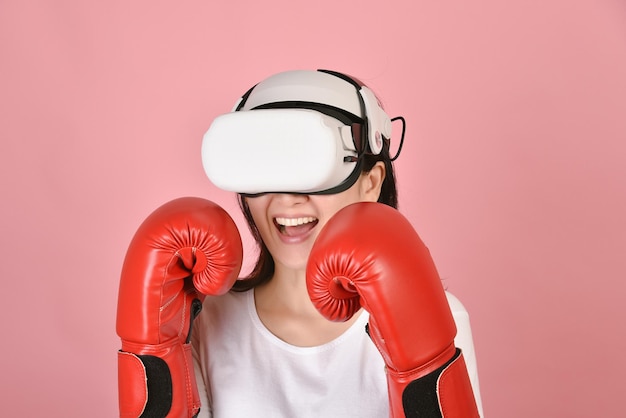 Mujer asiática que usa gafas vr Trabajando con la aplicación de videojuegos de punch boxing de auriculares de realidad virtual Mujer joven disfruta de una nueva experiencia de fitness con tecnología vr Foto de estudio