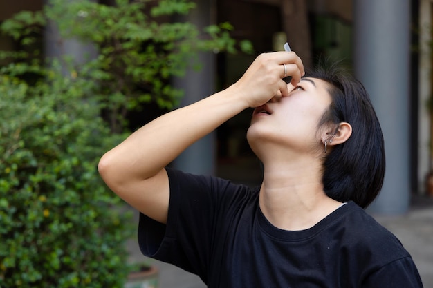 Mujer asiática que usa lubricante ocular para tratar el ojo seco o la alergia óptica