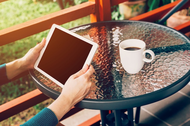 mujer asiática que usa la tableta en la tabla y café en el jardín con el vintage entonado.