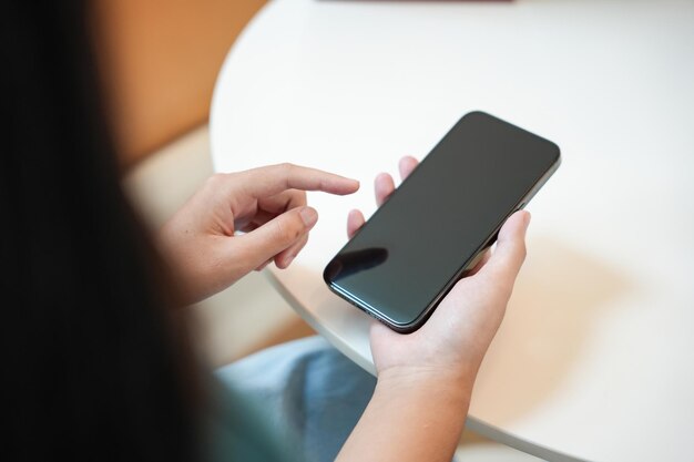 Foto mujer asiática que usa un teléfono inteligente adicta al móvil que pasa el tiempo revisando las noticias en las redes sociales