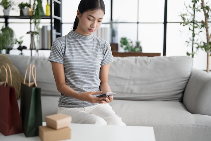 Foto mujer asiática que usa un teléfono inteligente para comprar en línea con bolsas de papel y cajas de papel marrón caja de cartón concepto de estilo de vida ecológico en el hogar con bolsa de compras