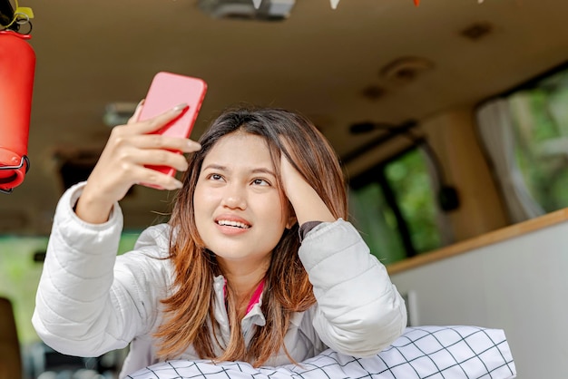 Mujer asiática que usa el teléfono móvil dentro de la autocaravana