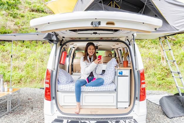 Mujer asiática que usa el teléfono móvil dentro de la autocaravana