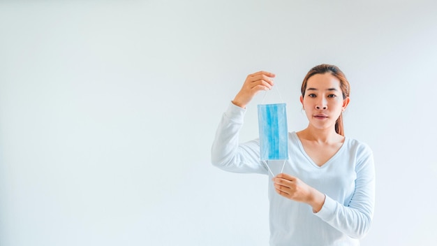 La mujer asiática se quita la máscara de protección para volver a la vida normal Coronavirus el concepto final