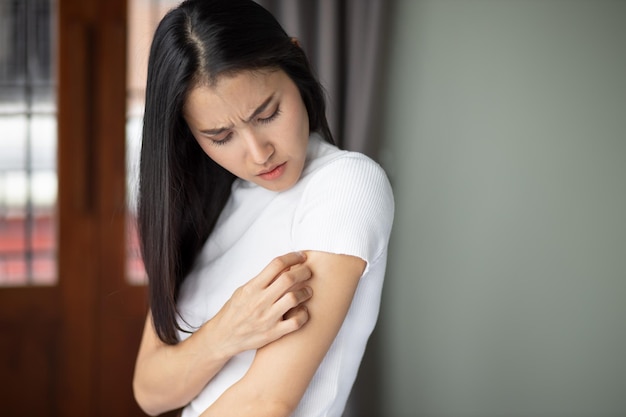 Mujer asiática rascándose la piel del brazo concepto de piel seca alérgica dermis inflamación hongo infección dermatología enfermedad eczema erupción cuidado de la piel