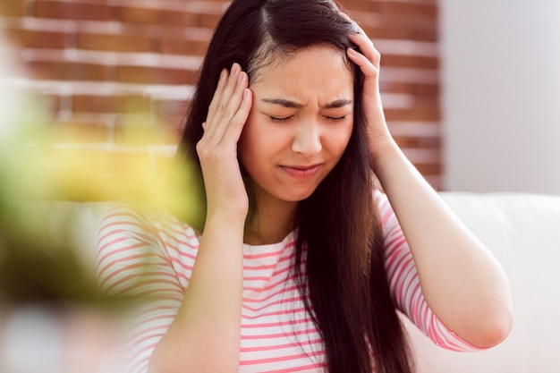 Mujer asiática recibiendo dolor de cabeza en el sofá