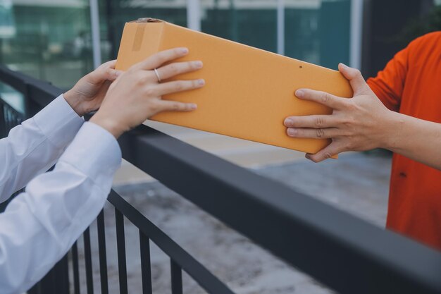 Foto mujer asiática recibiendo productos de un repartidor en el hogar joven propietaria mujer ordenando productos desde una aplicación de teléfono inteligente mujer con negocio en línea o concepto de pyme