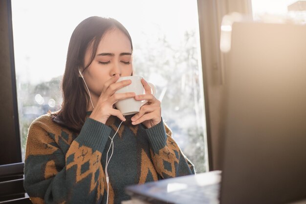 Foto mujer asiática relajándose y escuchando música en un café