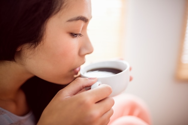 Mujer asiática relajante en el sofá con café