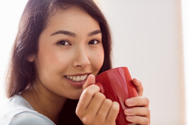 Mujer asiática relajante en el sofá con café