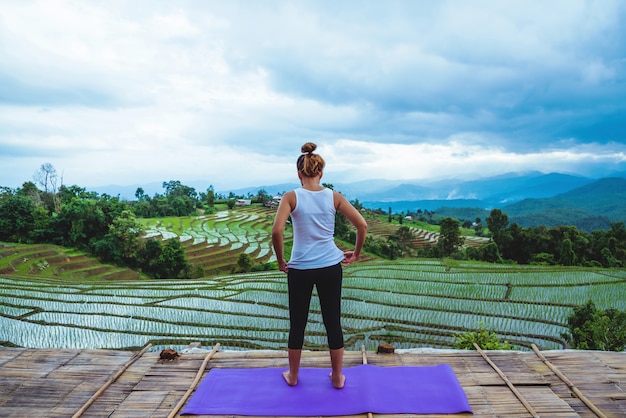 Mujer asiática relajarse en las vacaciones. Juega si yoga. En el balcón del campo natural del campo.