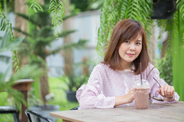 Mujer asiática del retrato que sonríe en cafetería.
