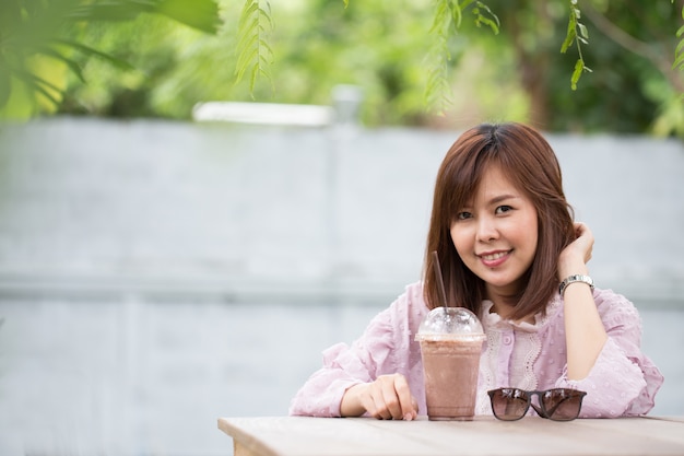 Mujer asiática del retrato que sonríe en cafetería.