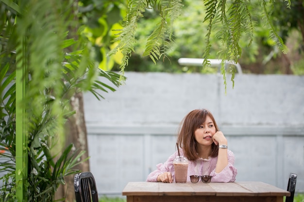 Mujer asiática del retrato que sonríe en cafetería.