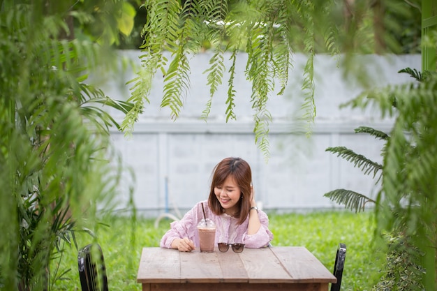 Mujer asiática del retrato que sonríe en cafetería.