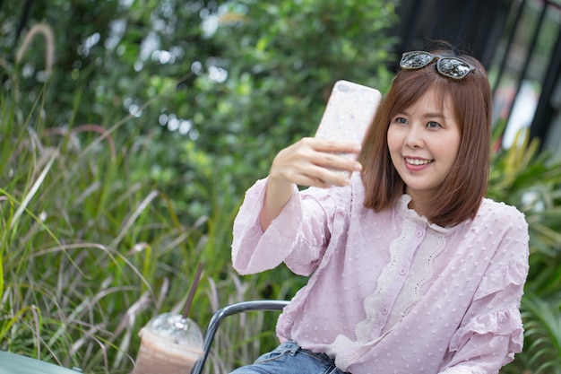 Foto mujer asiática del retrato que toma el selfie en cafetería