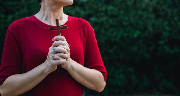 Mujer asiática rezando con cruz de madera y cree en Dios