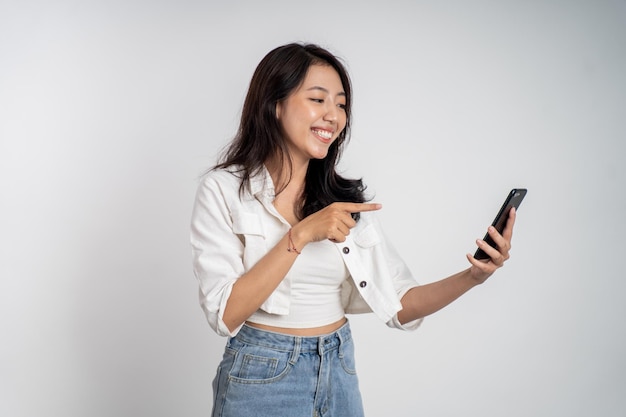 Mujer asiática riendo mientras mira la pantalla de su teléfono inteligente