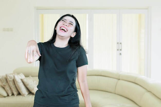 Mujer asiática riendo en voz alta al oír un chiste divertido en casa