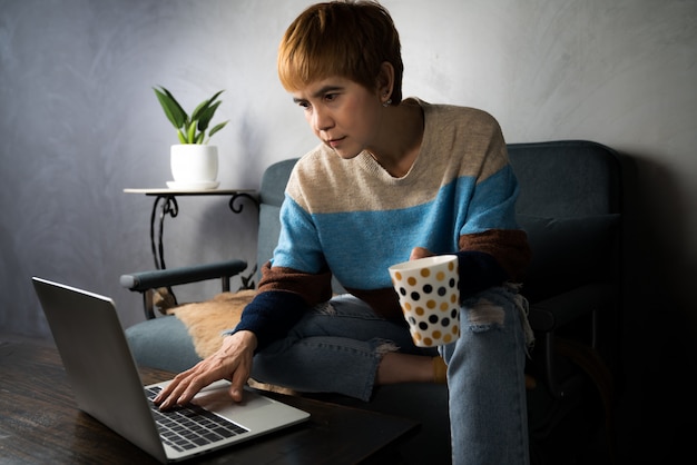 Mujer asiática en ropa casual usando laptop trabajando en interiores en casa