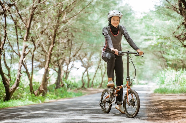 Mujer asiática en ropa deportiva y casco mientras monta en bicicleta