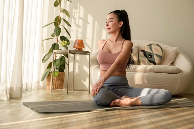 Foto mujer asiática en ropa deportiva haciendo ejercicio y yoga en la sala de estar de su casa