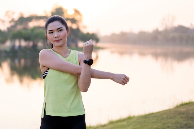 Una mujer asiática en ropa deportiva haciendo estiramientos antes de hacer ejercicio al aire libre en el parque