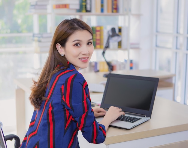 Mujer asiática segura descansa su mano sobre el teclado de la computadora portátil y da la vuelta