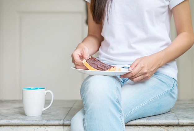 Mujer asiática sentada en una silla de mármol frente a la casa para desayunar por la mañana