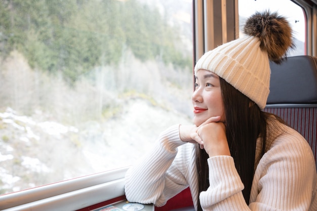 Mujer asiática sentada en un tren y mirando por la ventana