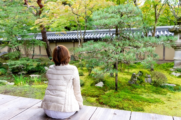 Mujer asiática sentarse y mirar el jardín de Japón