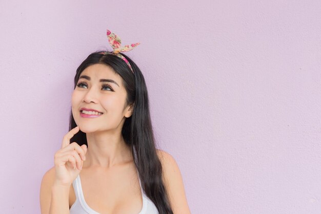 Mujer asiática sexy posar para tomar una foto sobre fondo rosa