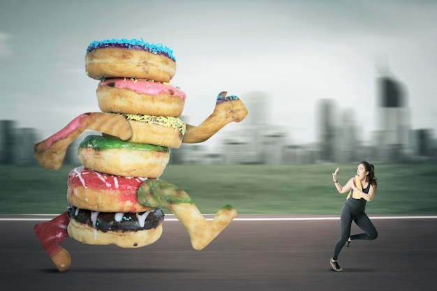 Foto mujer asiática siendo perseguida por rosquillas en las carreteras